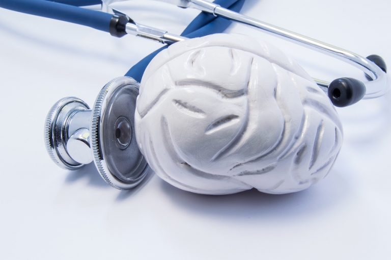 A stethoscope held up to a model of the human brain.