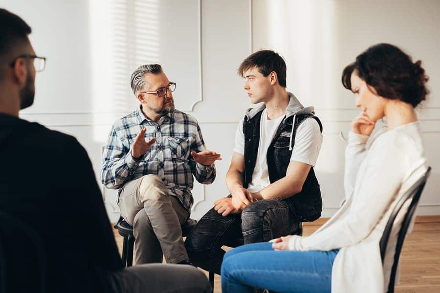 A therapist working with a group of people during a group therapy session in residential alcohol treatment.