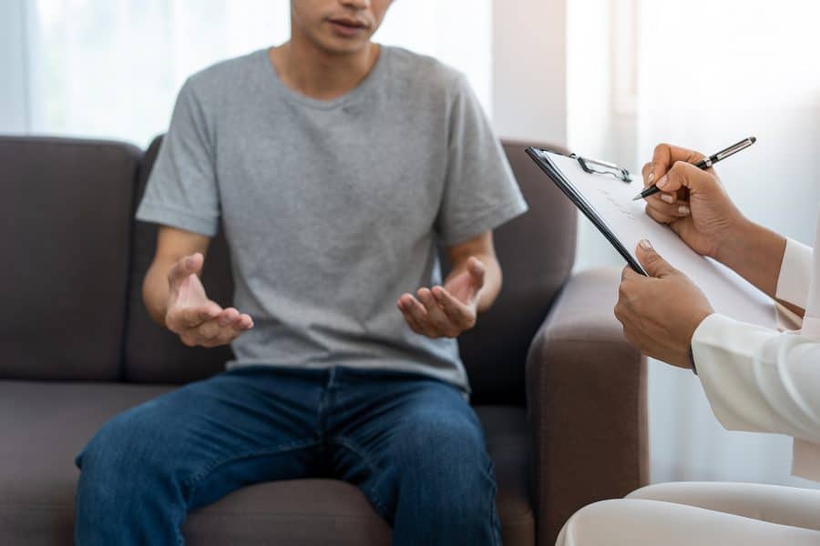 A man discussing his mental health recovery with a therapist.